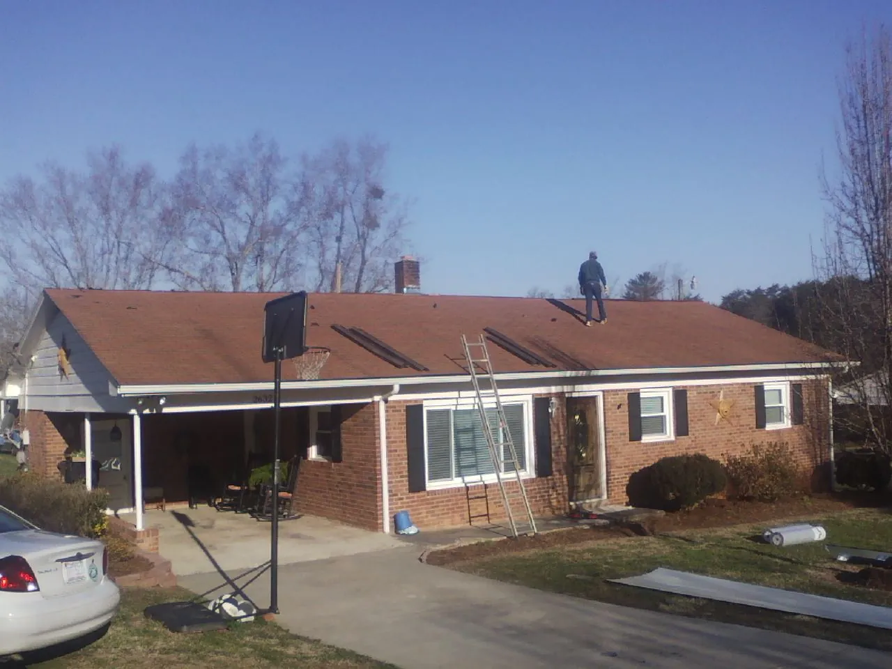 Roofer stripping a shingle roof on a brick ranch before metal panels in Argyle