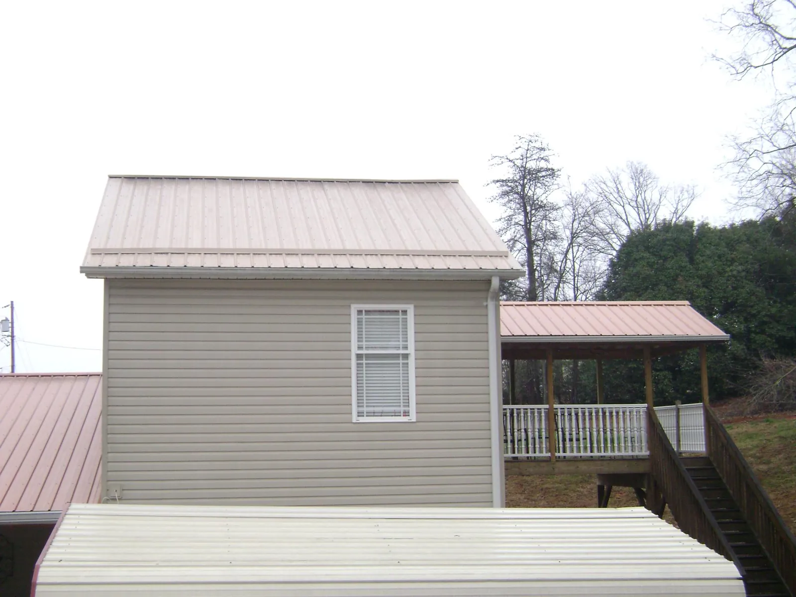 Tan metal roofs on a two story addition and attached porch, from a Roof Replacement job in Argyle