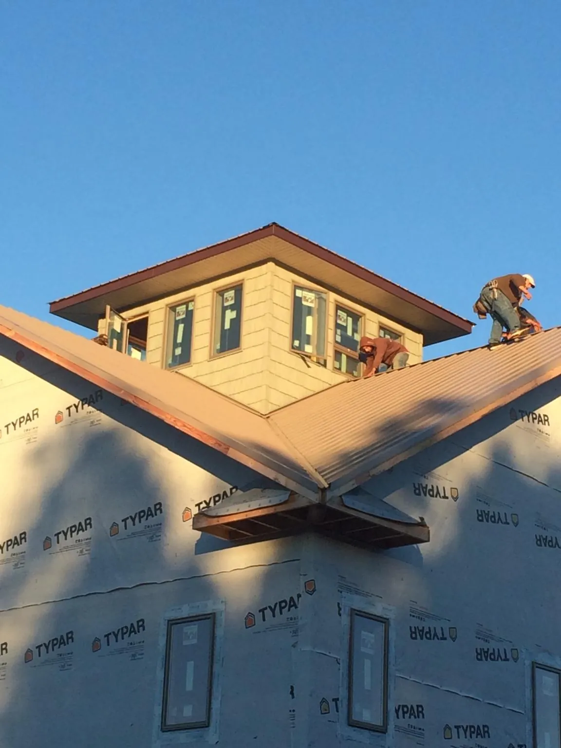 Roofers working around a rooftop cupola on a new metal roof at sunset — Roof Waterproofing in Argyle by Roofing Brothers